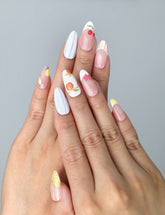 Hand model wearing pink almond-shaped press-on nails with hand-painted floral details and playful fruit elements